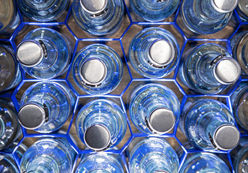 Multiple Glass Water Bottles With Pop Up Tops Organized In Blue Wire Holders.